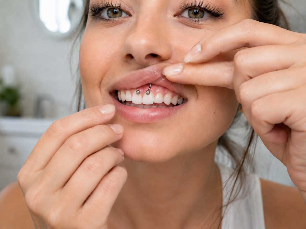 Frau mit Smiley Piercing pflegt ihr Piercing mit Kochsalzlösung