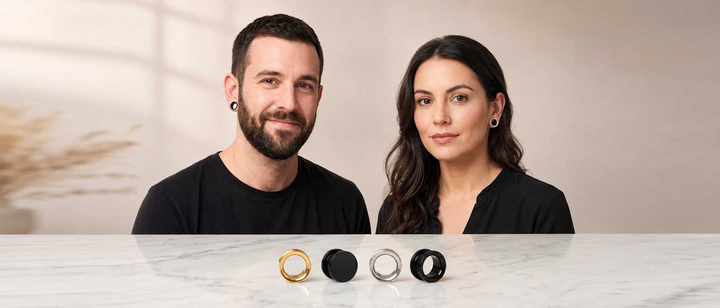 Mann und Frau mit kleinen 7mm Flesh Tunneln - außerdem einige 7mm Tunnel und Plugs auf Tisch präsentiert
